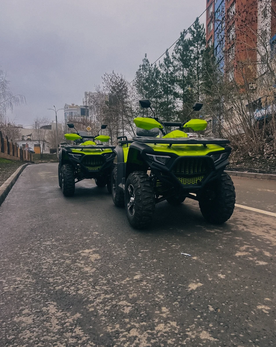 Два квадроцикла на дорожке у зданий.