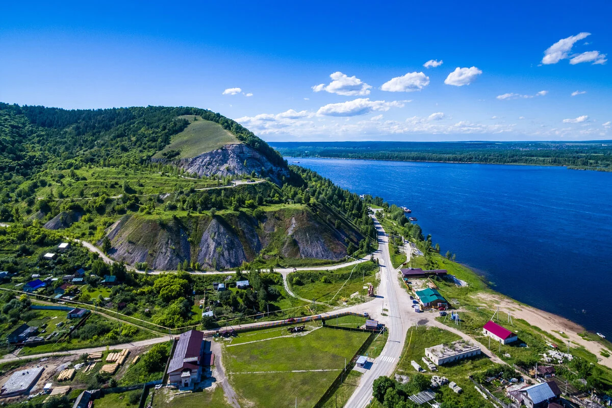 Посёлок, склон горы и широкая река, вид сверху.